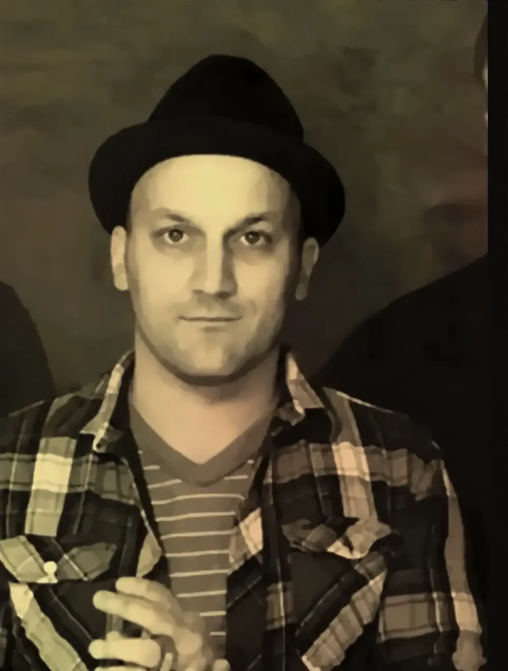 Mike Costanzo in a black hat and plaid shirt, looking straight out with a slight smile.